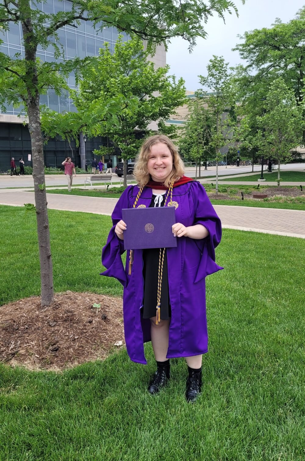 holding a diploma in purple regalia