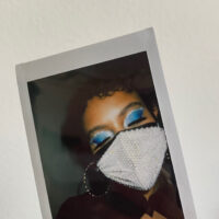 a polaroid picture of myself with blue eyeshadow and rhinestone mask