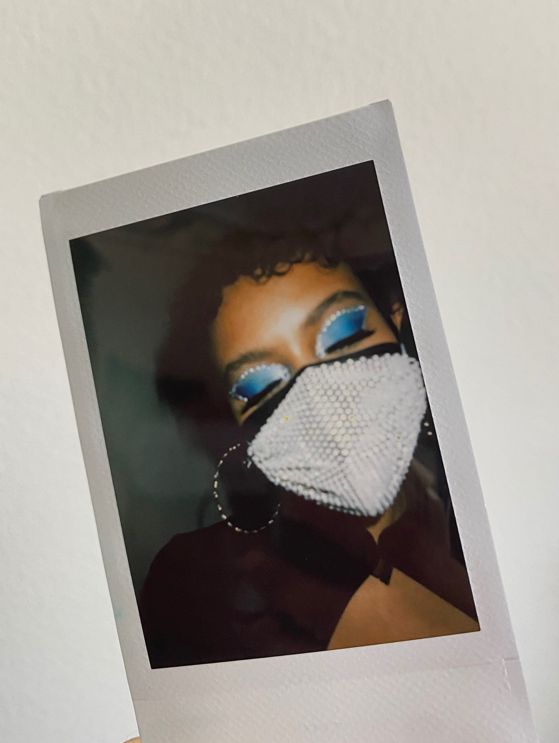 a polaroid picture of myself with blue eyeshadow and rhinestone mask