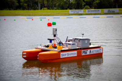 orange robotic boat with label "ship happens"