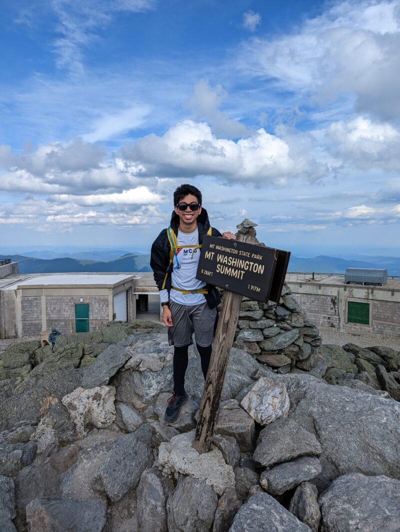 author with sign atop mount washington