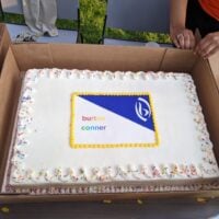 white sheet cake with Burton Connor and B1 logo written in white frosting