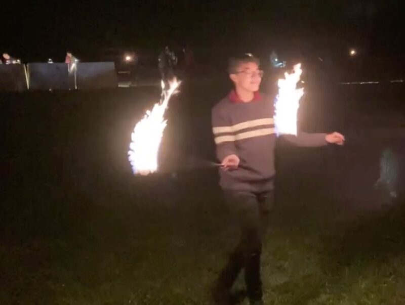 Me in a dark field. I'm holding two fire poi and each has a large trail of fire.