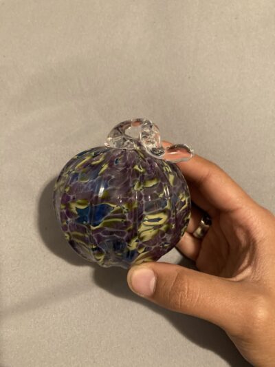An ornament with ribs (kind of like a pumpkin). It has swirls of purple, blue, and green.