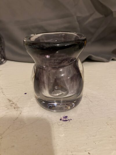 A small vase. It has thick sides causing an interesting refraction effect. The top of the vase is a dark purple and it fades to clear.