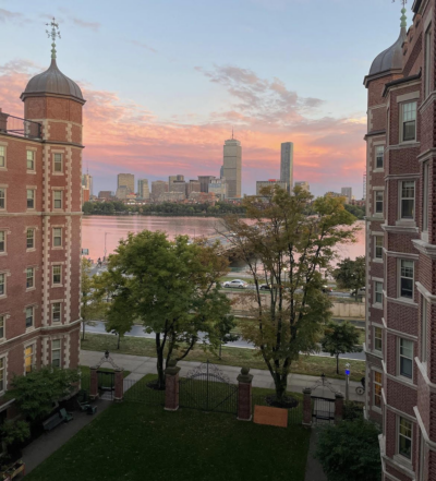A sunset as seen from Maseeh Hall. To the left and right parts of Maseeh are visible; in the middle is the courtyard, the river, and the Boston skyline across the river.