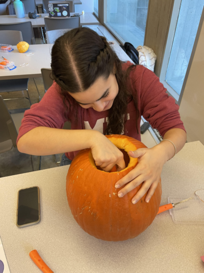 Favianna with her hand most of the way inside the open top of a pumpkin