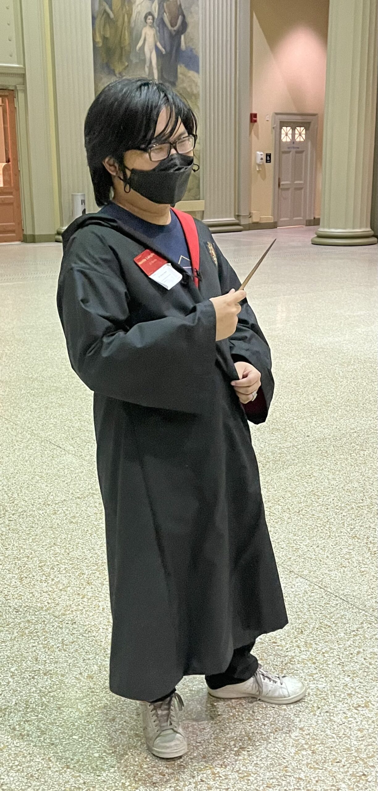 neville wearing robes and holding a wand