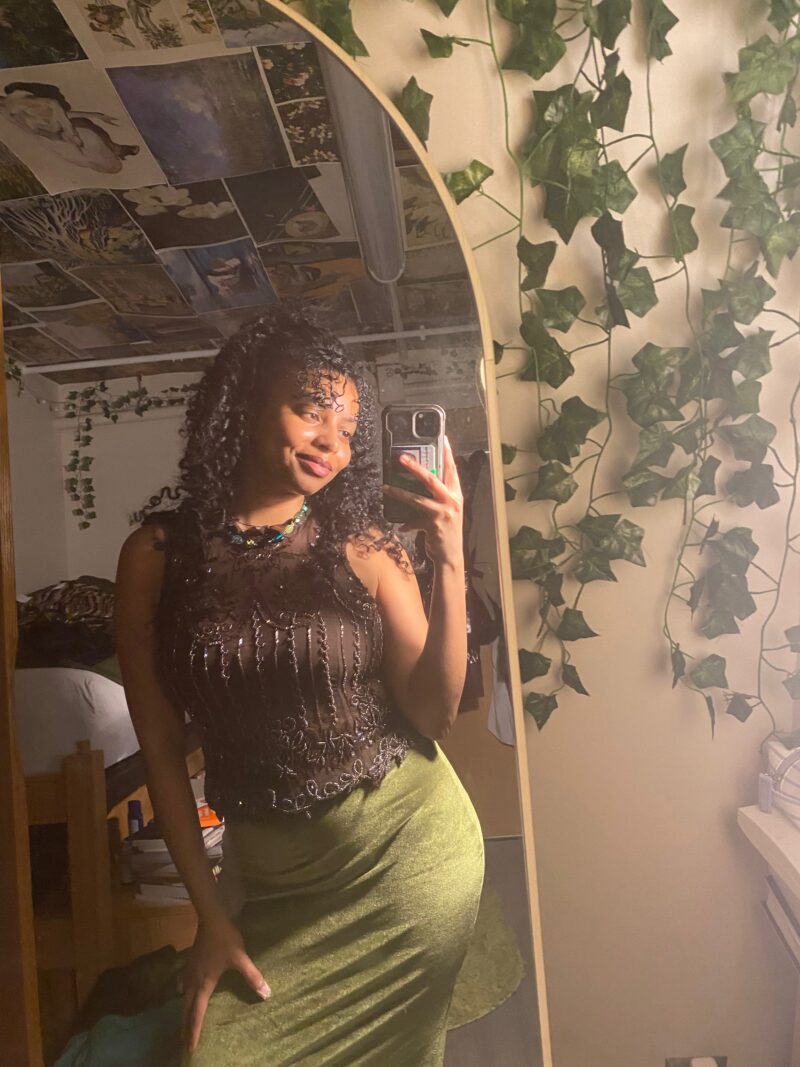 black woman wearing beaded brown shirt and green velvet skirt