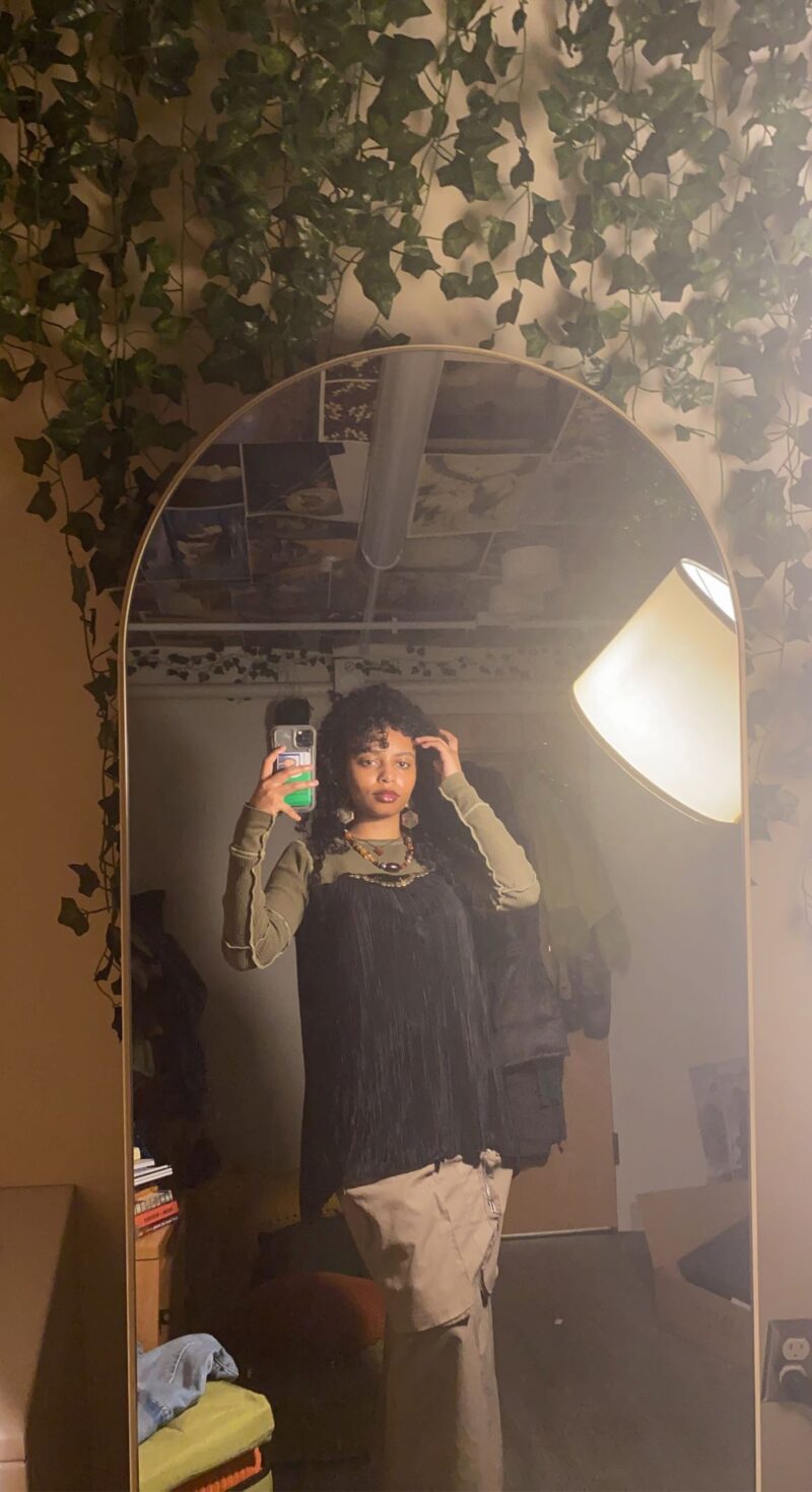 black woman wearing black top and brown skirt