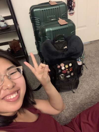 selfie of woman with her 2 suitcases and 1 backpack