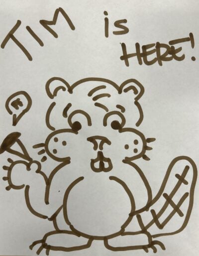 A drawing of Tim beaver in brown marker, holding a piece of pie and with the words "TIM is HERE" written on top.