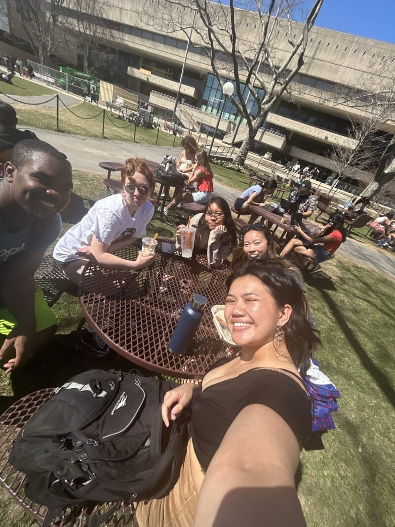 people crowded around a picnic table smiling and taking a photo