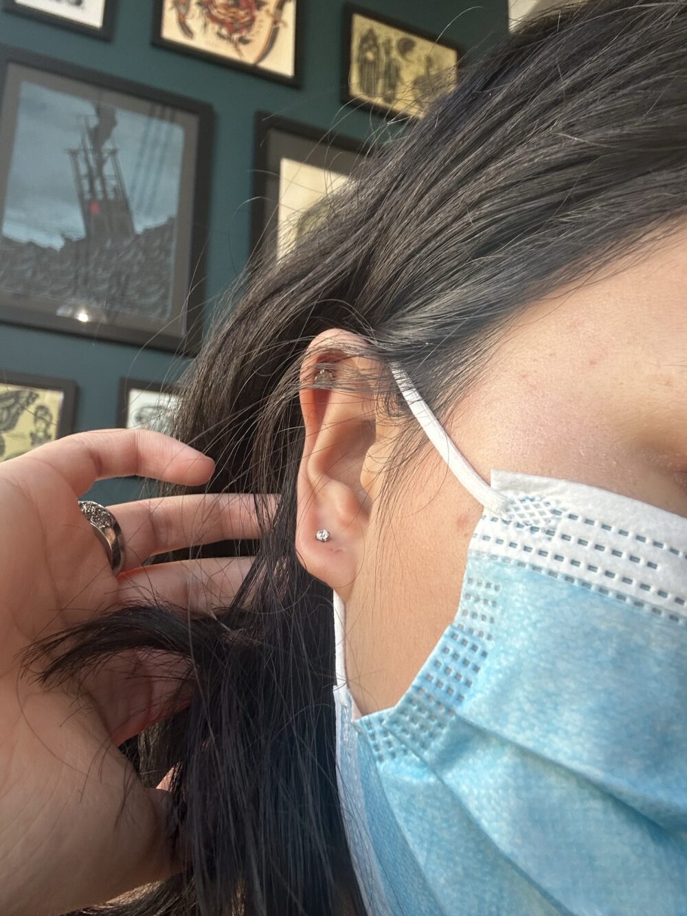 girl angling her ear to the camera to show off a piercing on her second lobe
