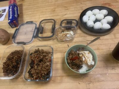 pakaprow, boiled eggs, and a bowl of rice laid out on a kitchen table