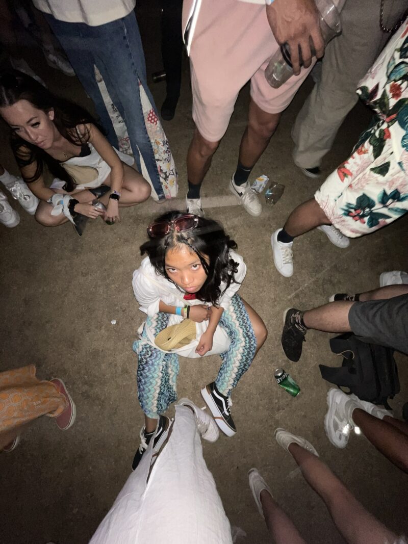 girl sitting on the ground looking up at the camera in a party setting