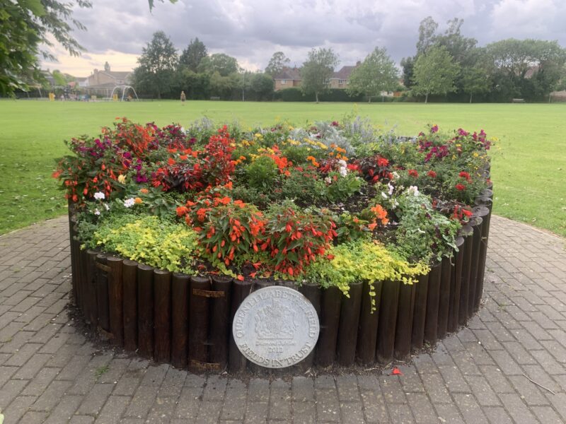 a collection of flowers in a fence circle of around 6 ft diameter