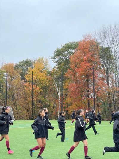 Soccer team running with fall leaves in background.