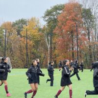 Soccer team running with fall leaves in background.