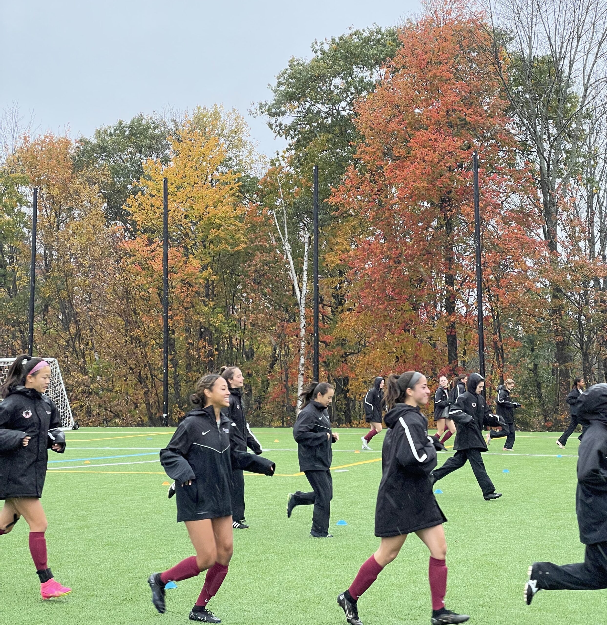 Soccer team running with fall leaves in background.