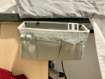 Grey bedside storage caddy hanging on the side of a bed