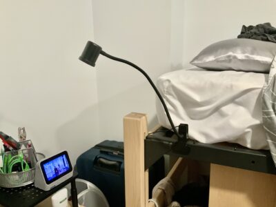 Black clip-on lamp clipped to the side of a bed