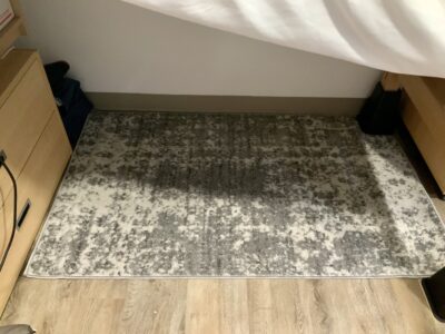 Grey & cream mottled rug on floor beneath bed