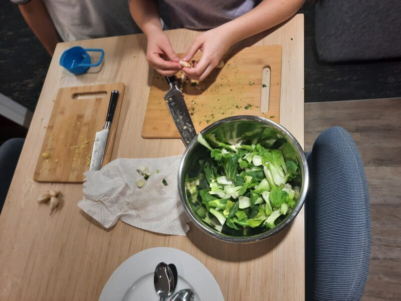 Bowl of bok choy, two cutting boards, & some garlic