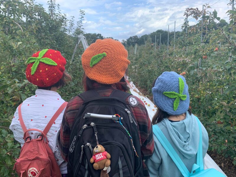 three people wearing strawberry, orange, and blueberry hats