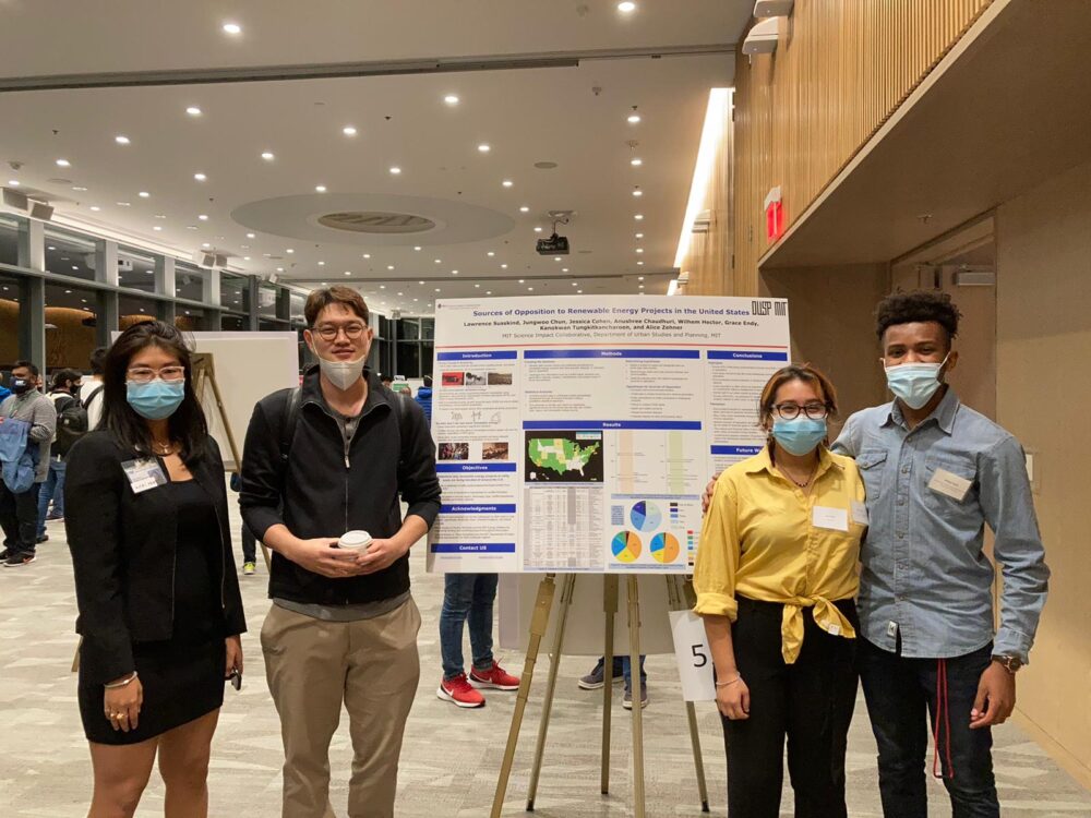 4 researchers standing next to their poster