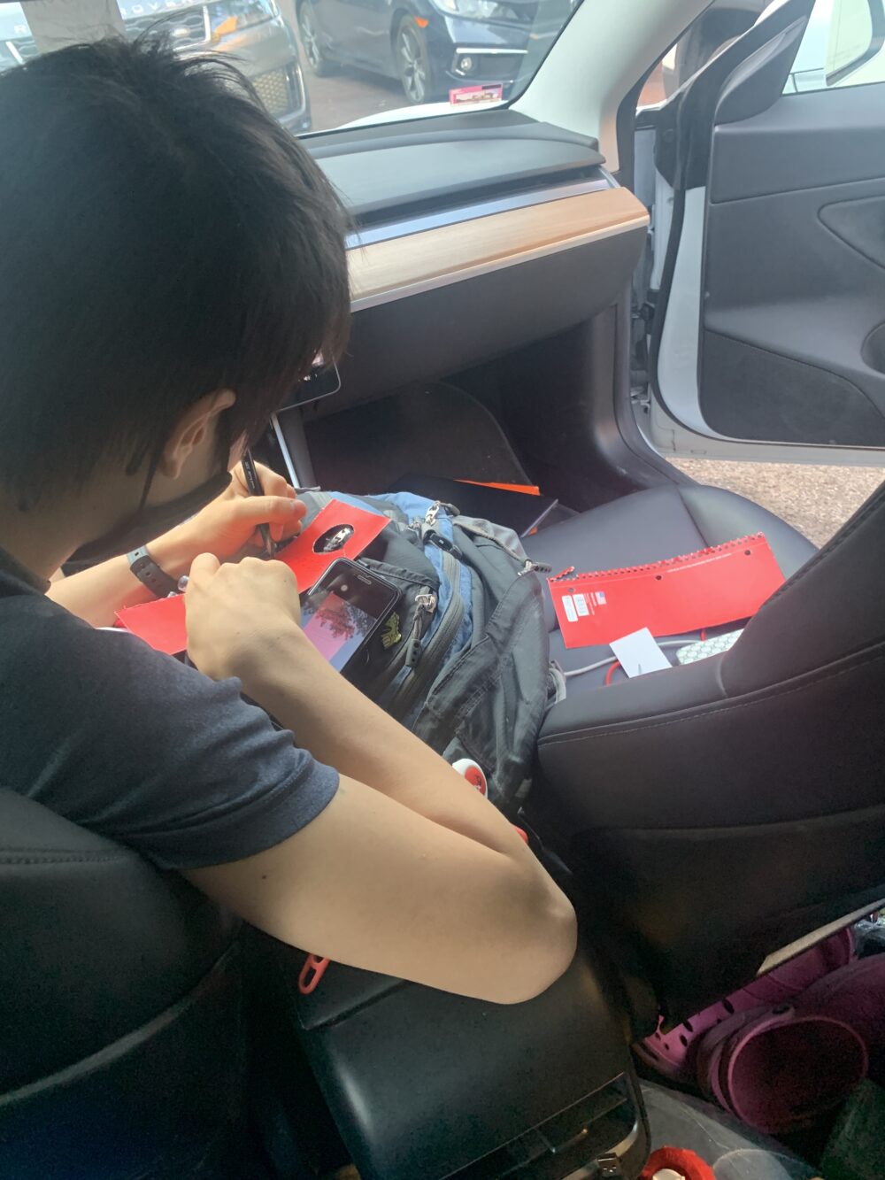 a guy writing on red paper in a car