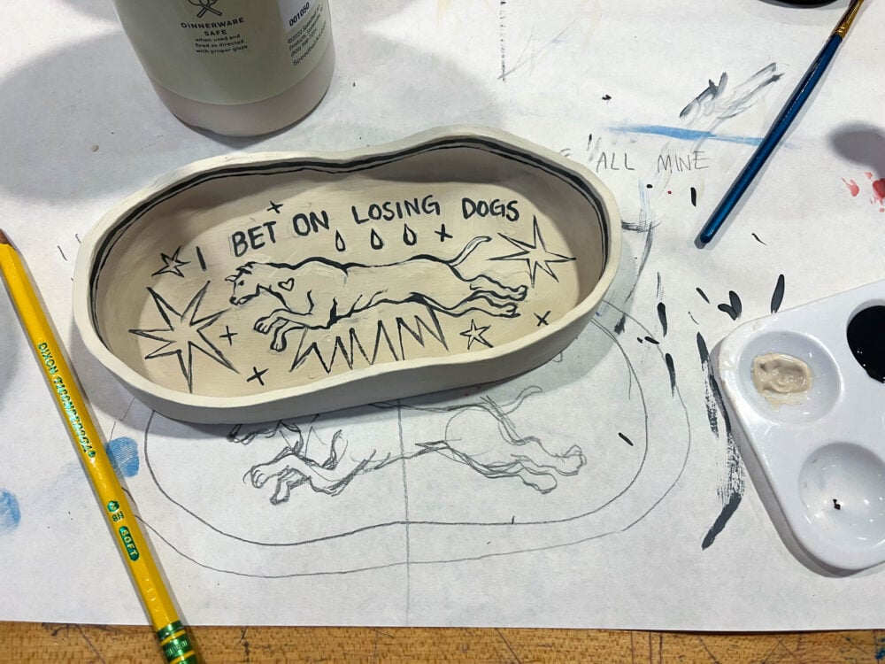 a picture of a white oval-shaped tray with the words "I bet on losing dogs" and a drawing of a dog on it