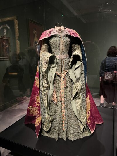 a picture of an elaborate light green gown with long, billowing sleeves and a red and gold cape