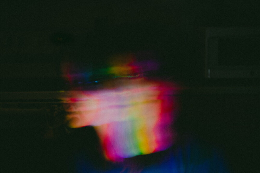 a picture of a blurred, multicolored face slowly moving left. the background is black