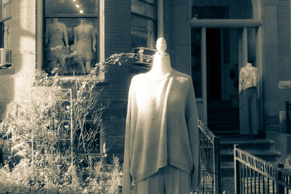 an almost monochromatic picture of several headless mannequins in front of a store