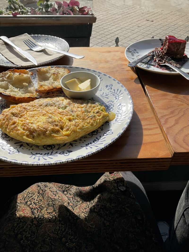 an omelette, bread, and red velvet cake on a tabke