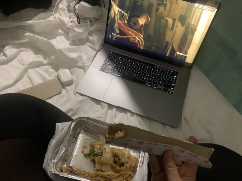 person eating leftovers while watching a show on her laptop