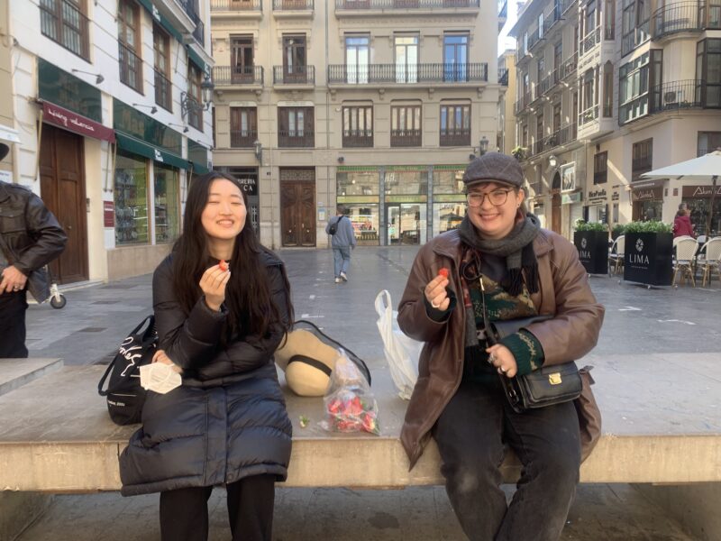 two people eating strawberries in a city square