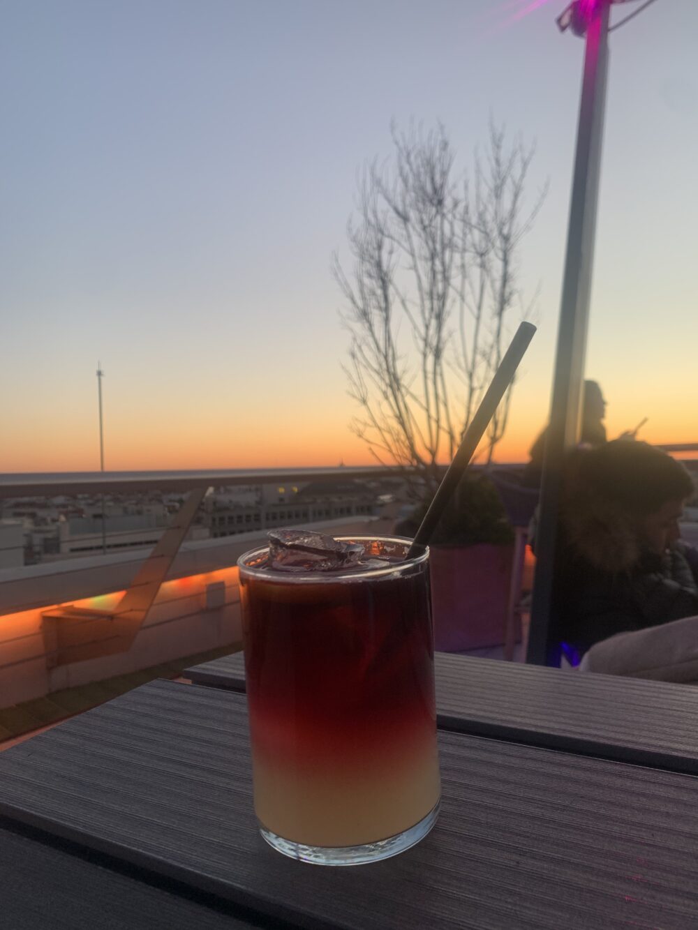 a red and orange cocktail against a sunset