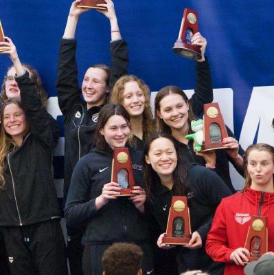 Swim team holding up their trophies.