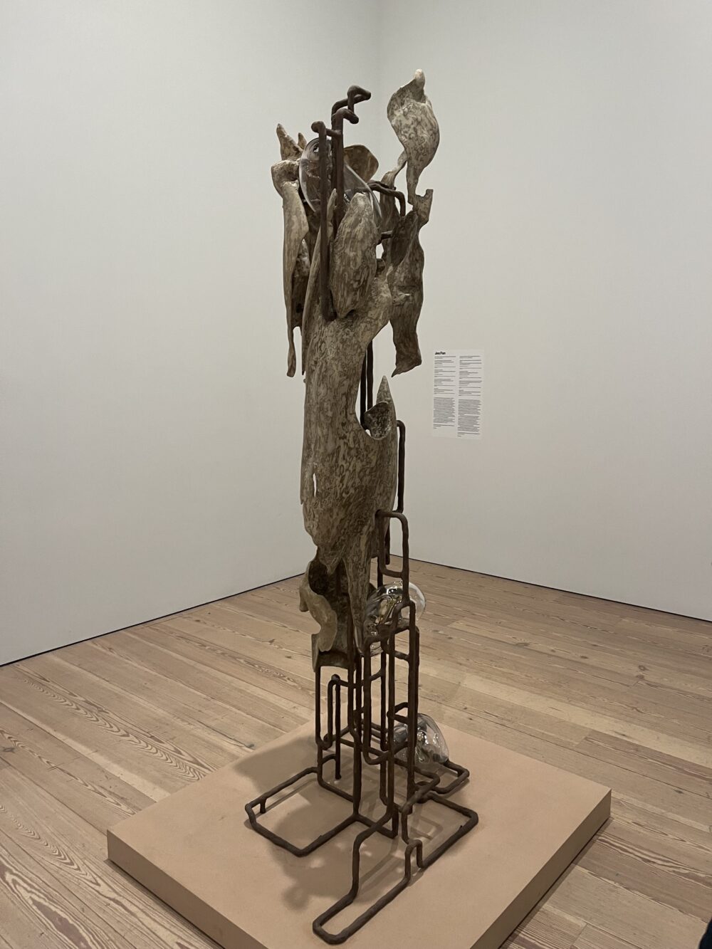 a photo of a free-standing sculpture consisting of a metal frame, cast bone-like elements, and amorphous glass forms.