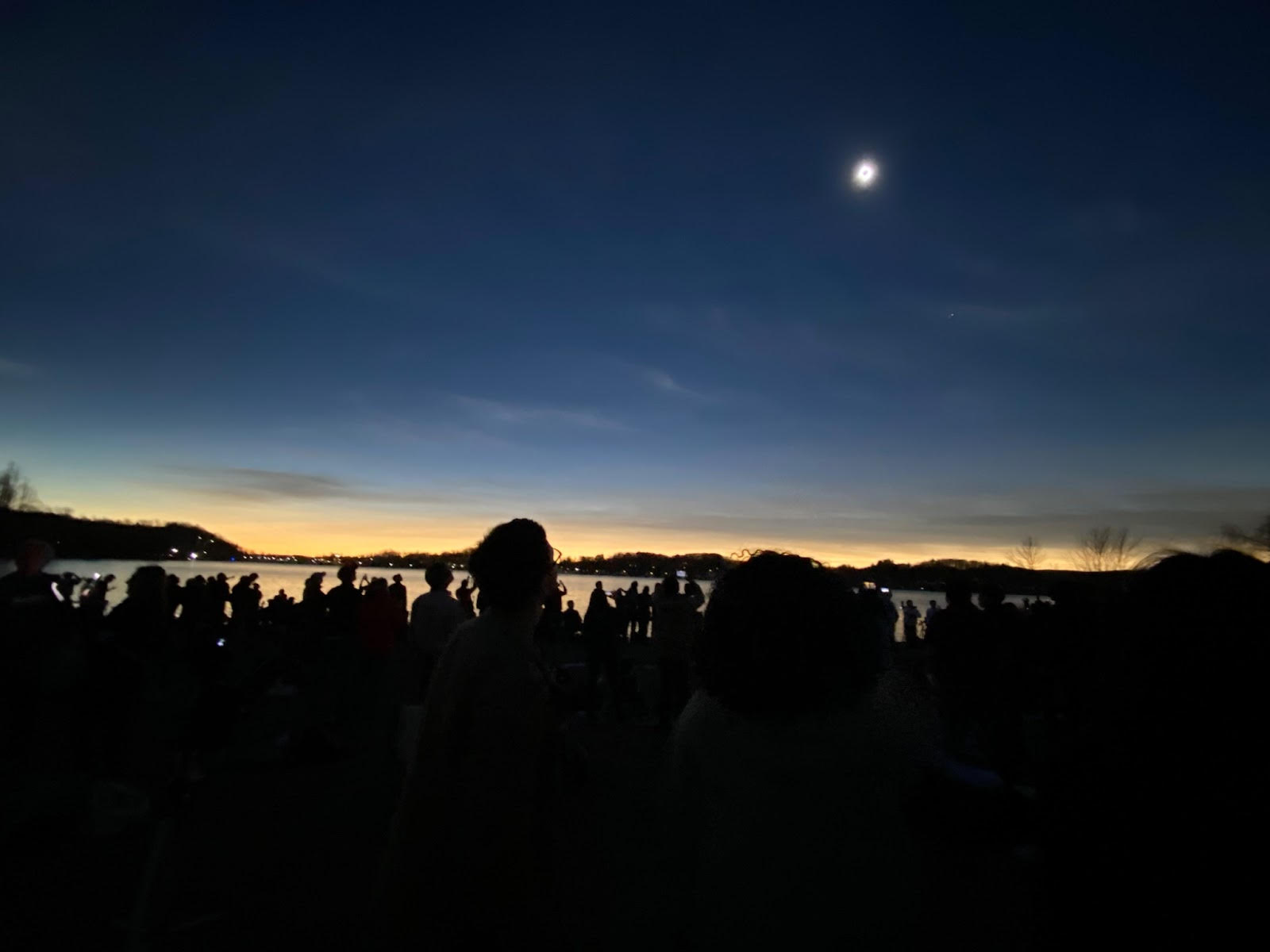 picture of totality against a setting sky with people as silhouettes