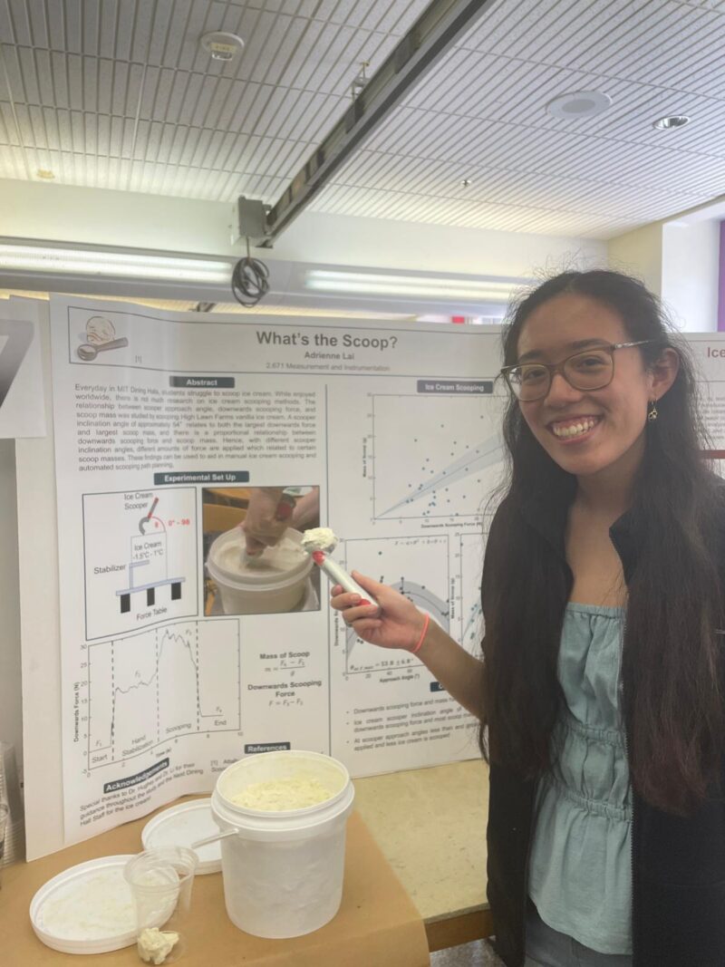 Presenter scooping ice cream in front of her poster.