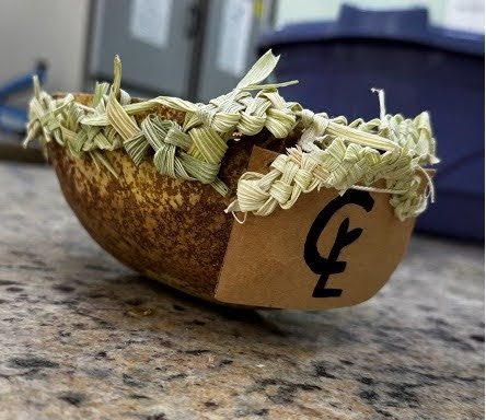A container made from organic materials, including grasses and wood shavings.
