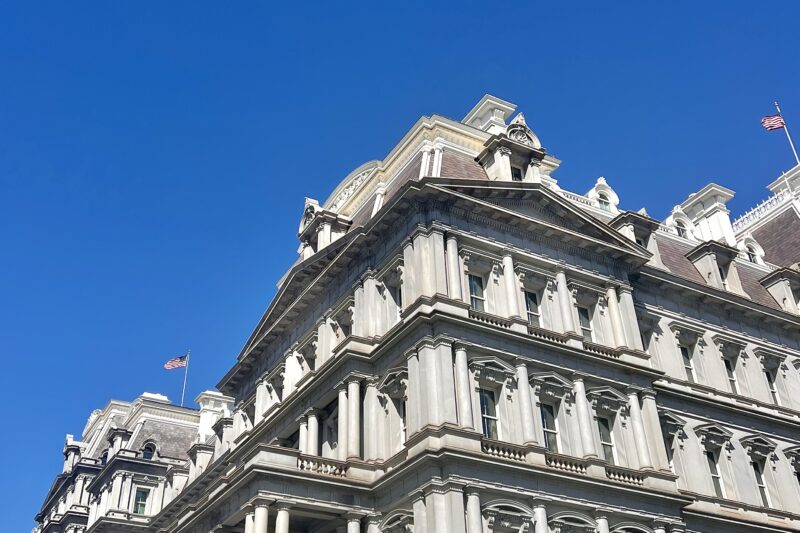 Blue sky with no clouds in the back of a white, fancy building.