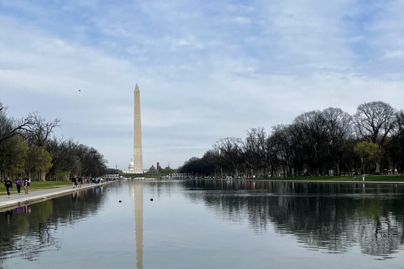 Washington monument, reflecting pool in front. Trees line the sides.