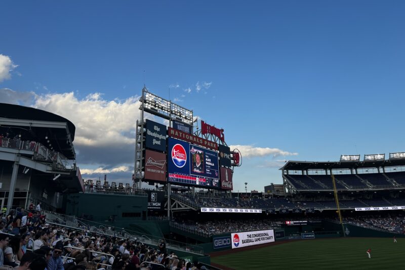 Baseball stadium mostly filled. Sign at bottom reading