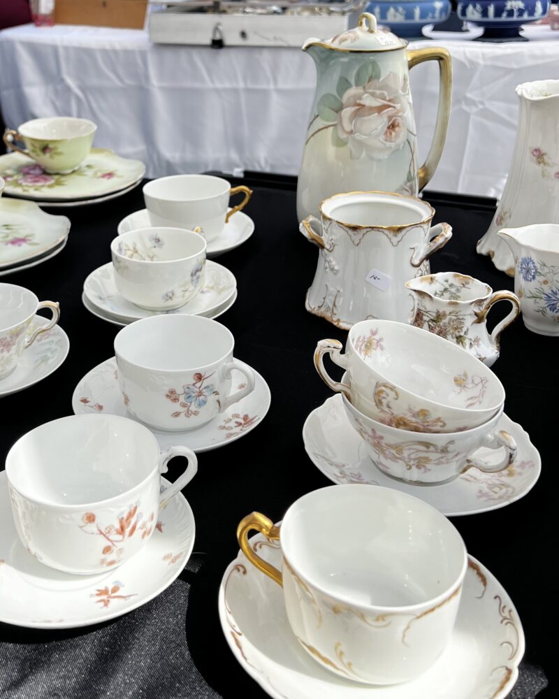 Black table with white, floral tea cups and saucers.