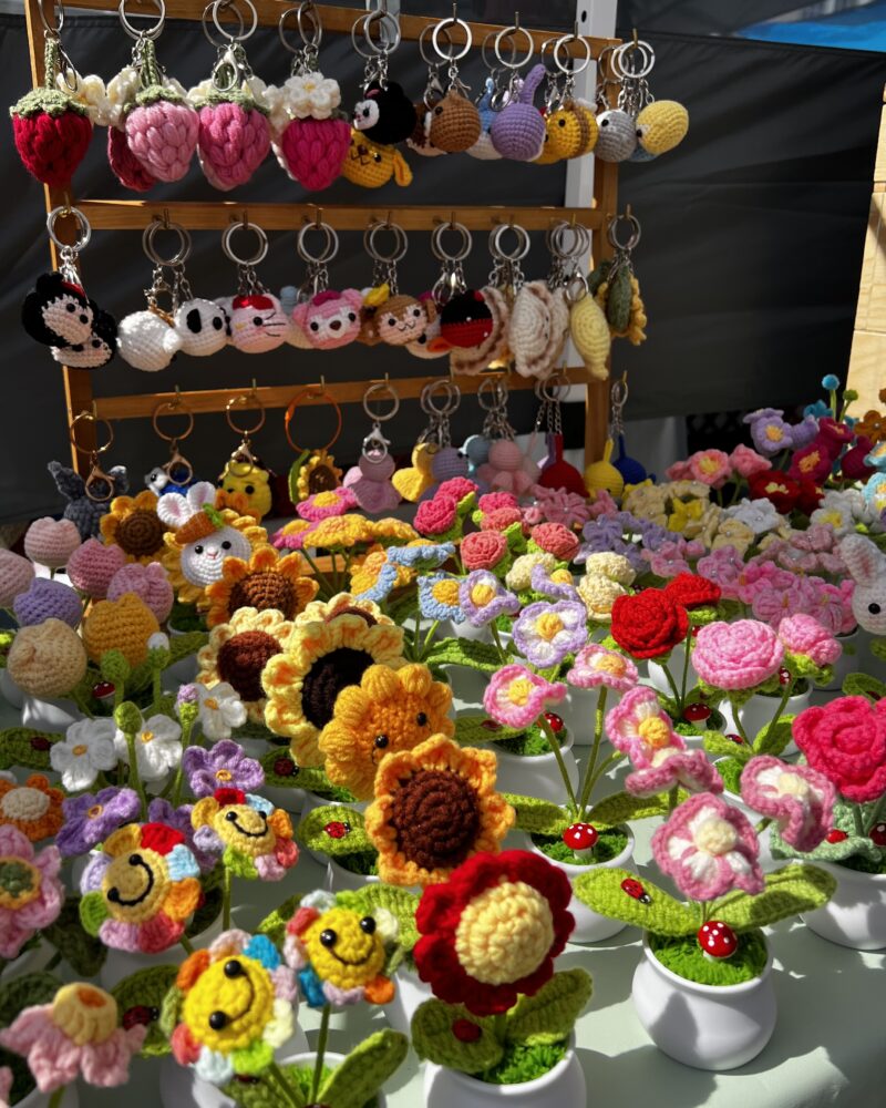Crochet keychains (strawberries, animals) and crochet flowers (roses, sunflowers, tulips) in a pot.