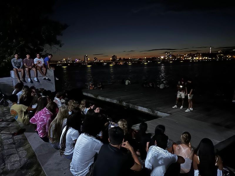 Group of men's and women's soccer on side of river.